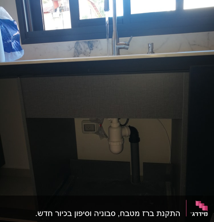 כיור מטבח עם ברז וצנרת מתחת לארון